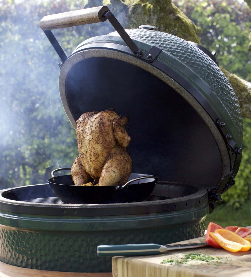 Green big egg bbq met een hele kip op standaard
